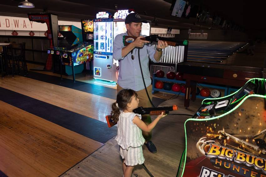 Dad and daughter playing an arcade game
