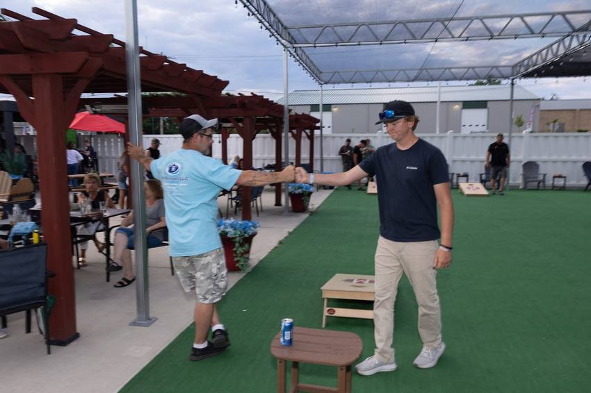 Friends playing cornhole on the Midway patio