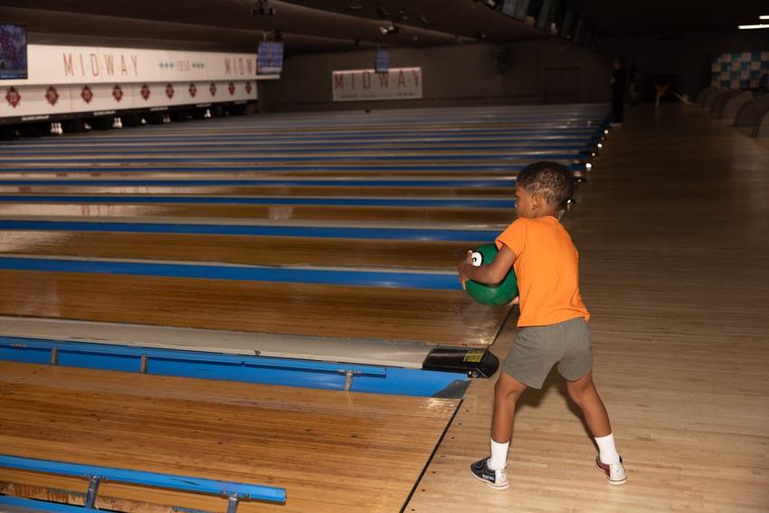 A young bowler rolling a ball down the lane