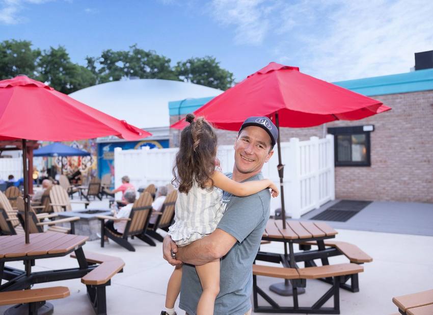 A dad holding his daughter on the Midway patio