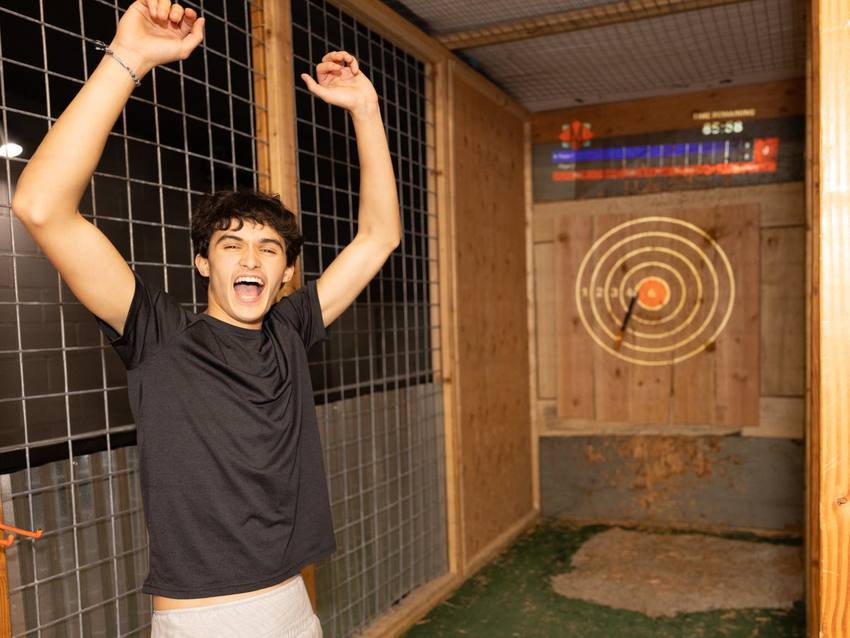 A teen celebrating at axe throwing